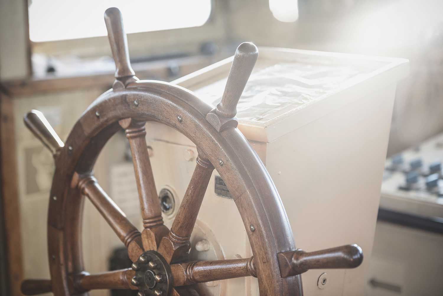 Old wooden steering wheel on modern tugboat